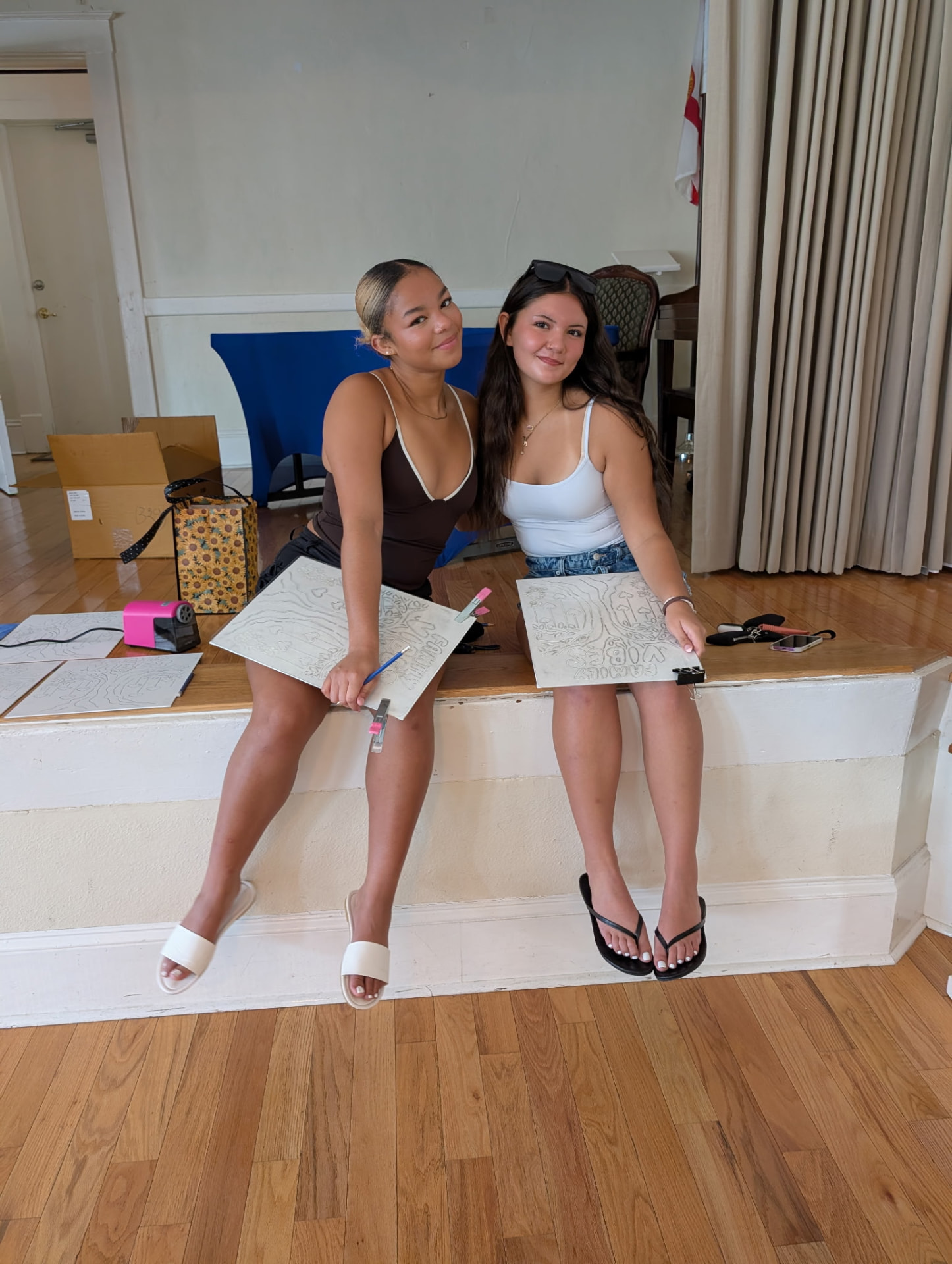 Two cousins showing off their pencil-sketched Family Vibes canvases