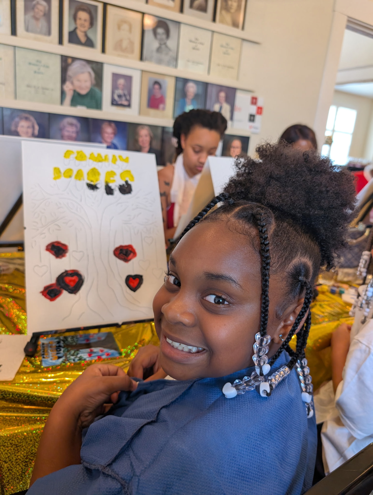 A young Chandler artist smiling beside her red-hearts Family Vibes canvas