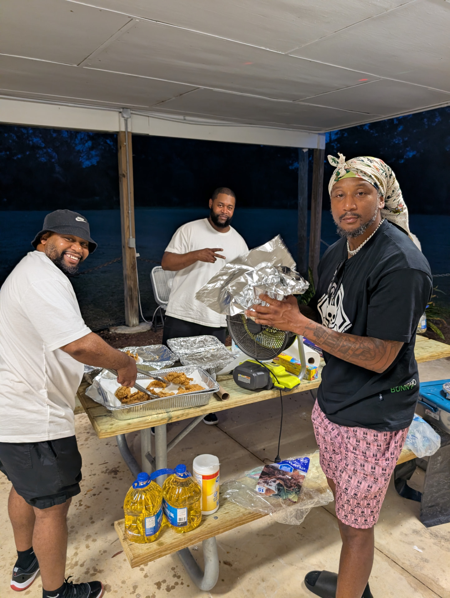 The cooking crew frying up dinner under the pavilion at dusk