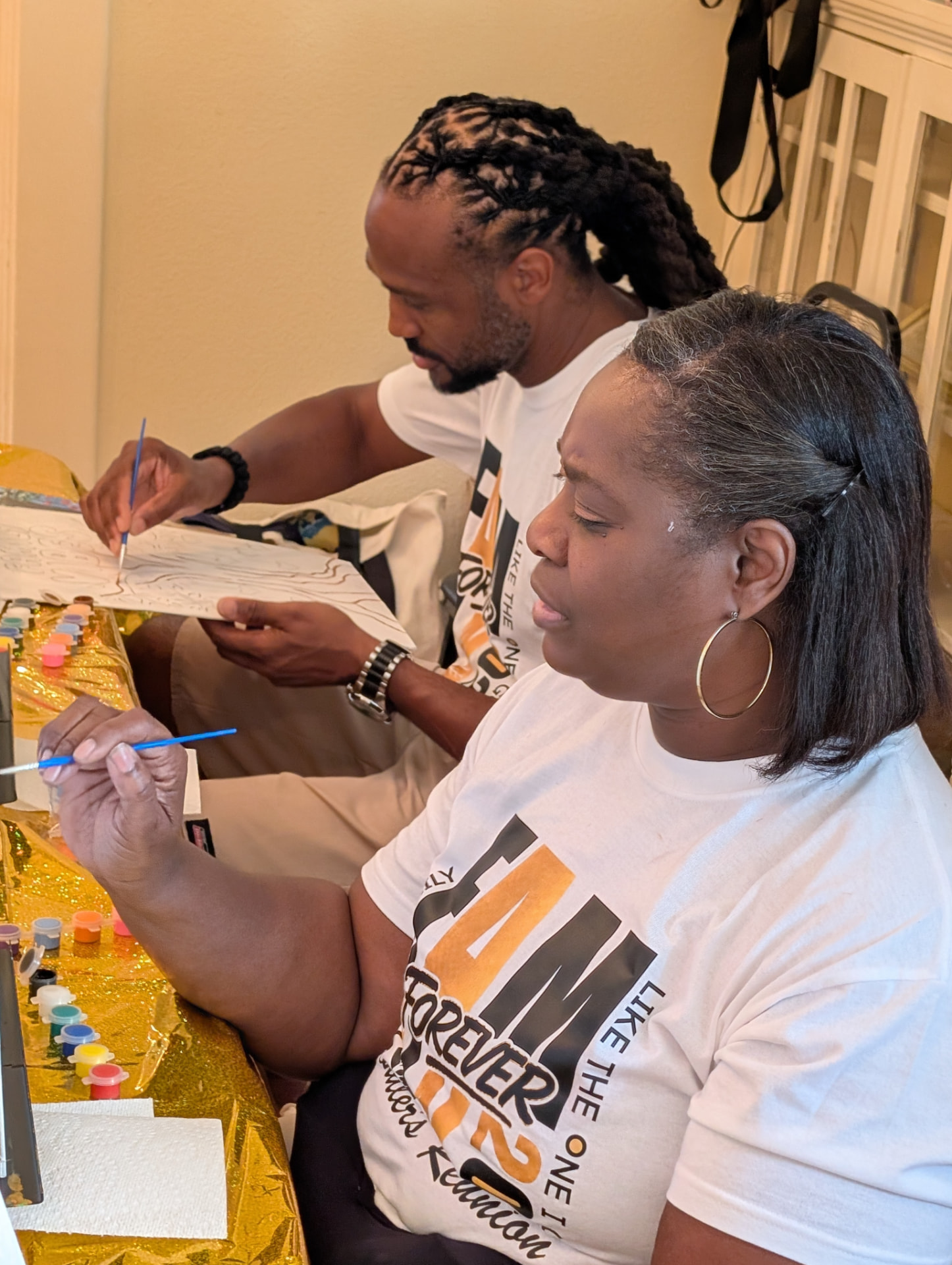 Two family members in Fam Forever reunion tees painting side by side